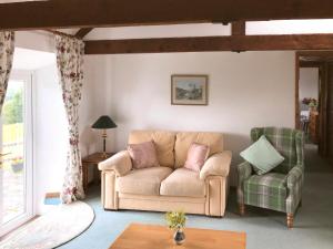 un salon avec un canapé et deux chaises dans l'établissement Cych Cottage, à Capel-Ifan