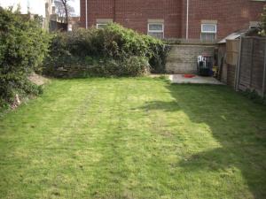 a yard with a large lawn with a brick building at Open plan flat with large garden close to beach in Bournemouth