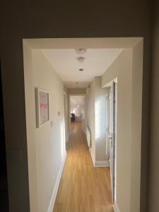 a hallway with white walls and wood floors at Open plan flat with large garden close to beach in Bournemouth +1 photo