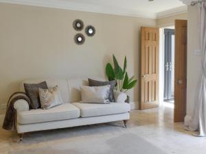 a white couch in a living room with a plant at The White House Retreat in Findon