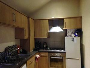 a kitchen with wooden cabinets and a white refrigerator at Open plan flat with large garden close to beach in Bournemouth