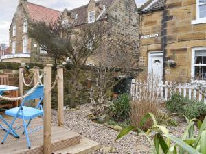 ein blauer Stuhl auf einer Holzterrasse vor einem Haus in der Unterkunft Quaker's Cottage in Carlin How