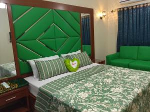 a bedroom with a large bed with a green headboard at Hotel White Palace Clifton in Karachi