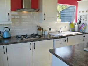 a kitchen with white cabinets and a sink and a stove at The Gallery in Mevagissey