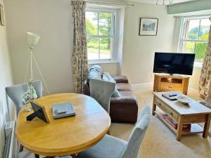 a living room with a table and a television at Staffield Cottage in Kirkoswald