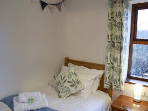 Schlafzimmer mit einem Bett mit einem Fenster und einem Kissen in der Unterkunft Capstan Cottage in Whitby + 5 Fotos