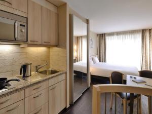 a hotel room with a kitchen and a bedroom at Aparthotel Adagio Genève Mont-Blanc in Geneva