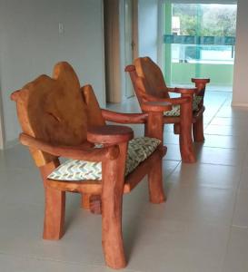 grupa drewnianych krzeseł siedzących w pokoju w obiekcie Sonho de Verão - Casa de Praia, Pitimbu PB - 50 Metros do mar - QUASE PÉ NA AREIA w mieście Pitimbu