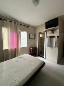 a bedroom with a large bed and a window at Hotel Fênix in Salvador