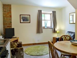a living room with a table and a kitchen at Ardennes Cottage in Sewerby