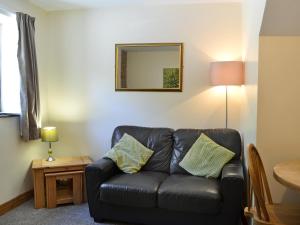 a black leather couch in a living room with a mirror at Ardennes Cottage in Sewerby