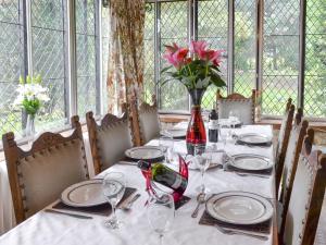 a dining table with a vase of flowers on it at The Sanctuary in Little Chart +20 photos