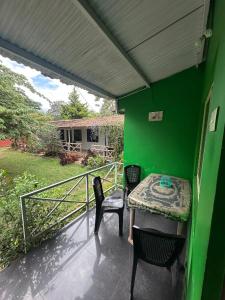 a balcony with a table and chairs on a green wall at The Big Cat's Den - Maravakandy Resort, Masinagudi in Masinagudi