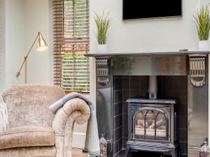 ein Wohnzimmer mit einem Stuhl und einem Kamin in der Unterkunft Cottage - Uk48472 in Lintz Green