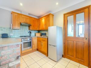 une cuisine avec des armoires en bois et un réfrigérateur blanc dans l'établissement Chestnut Cottage - Uk45580, à Maltby le Marsh