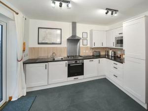 una cucina con mobili bianchi e un forno a piano cottura di Single Malt Cottage a Geary