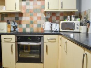 a kitchen with white cabinets and a black oven at Fisherman's Cottage in Sheringham