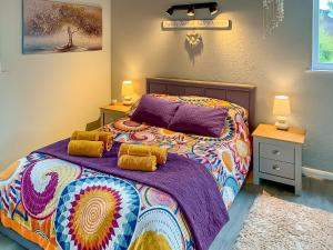 1 dormitorio con 1 cama colorida y 2 mesitas de noche en Valley View Lodge, en Bideford