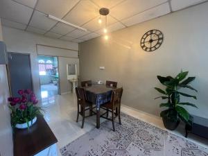 a dining room with a table and a clock on the wall at Uncle J homestay in Marang