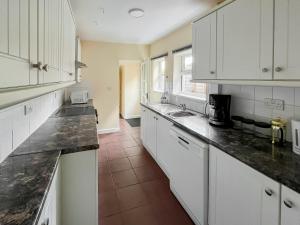 una cucina con armadietti bianchi e ripiani neri di Billada Cottage a Firsby