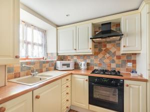a kitchen with white cabinets and a stove top oven at The Dairy - Uk37518 in Routh
