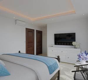 a white bedroom with a bed and a flat screen tv at Luna Oriental in Phu Quoc