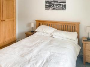 a bedroom with a white bed with a wooden headboard at Chainbridge Cottage in Whitby