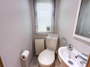 a bathroom with a white toilet and a sink at Lovely Dog Friendly Caravan For Hire At California Cliffs, Norfolk Ref 50027K in Great Yarmouth +17 photos