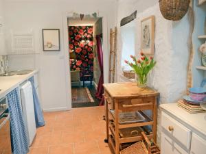 eine Küche mit einem Tisch mit einer Vase mit Blumen darauf in der Unterkunft Ragwood Cottage in Weare