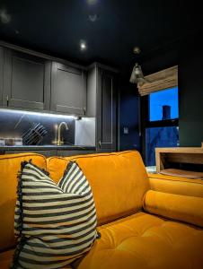 a yellow couch with a striped pillow in a kitchen at The Hideaway Bureau - Islay in Wooler