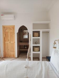 Un dormitorio con una cama blanca y una puerta de madera. en Riad DabaKech, en Marrakech 13 fotos más