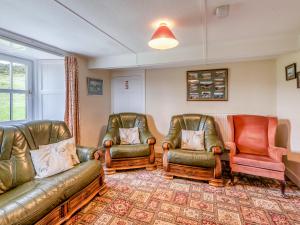 een woonkamer met leren banken en stoelen bij Haweswater Cottage in Bampton