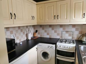 a kitchen with white cabinets and a washing machine at Charlie's House Relaxing Farmhouse near Letterkenny 
