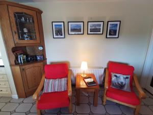 a living room with two red chairs and a table at Charlie's House Relaxing Farmhouse near Letterkenny 