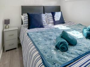 a bed with blue sheets and blue pillows on it at Chalet 54 in Cromer