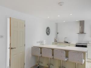 a kitchen with white walls and a counter with chairs at Sea Escape in Heacham +5 photos