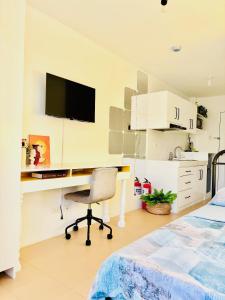 a bedroom with a desk with a monitor and a chair at Studio By The Sea in Dumaguete