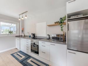 a kitchen with white cabinets and a stainless steel refrigerator at Water's Edge Holiday Home in Beadnell