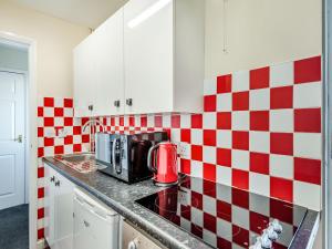 a kitchen with red and white checkered tiles on the wall at Rainbow Bungalow 2 - Uk39810 in Chapel Saint Leonards