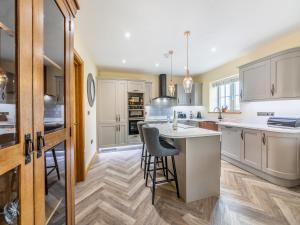 a kitchen with white cabinets and a island with bar stools at Garth House - Peel Castle in Brampton +26 photos