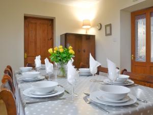 ein Tisch mit Tellern und Schüsseln und einer Vase mit Blumen in der Unterkunft Tirmynydd Farm Cottage in Dunvant