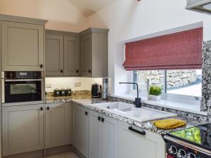a kitchen with white cabinets and a sink and a window at Lower Stables in Newlyn