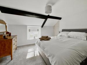 una camera bianca con un grande letto e un comò di Lawns Cottage a Helmsley
