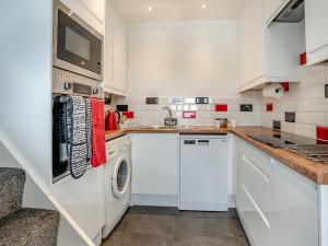 a kitchen with white cabinets and a washer and dryer at Stable Cottage - Uk10694 in Amroth +26 photos