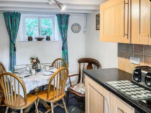 a kitchen with a table and chairs in a kitchen at Fedwr Gog Cottage in Llangwm