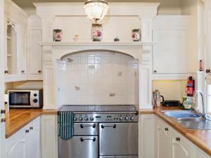 cocina con armarios blancos y estufa de acero inoxidable en Luppincott Chambers - Hpps, en Bideford