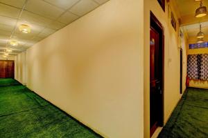 a hallway with a white wall and a red door at SPOT ON Rainbow Lodge in Guwahati