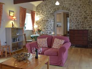 a living room with a purple couch and a table at Gwili Cottage in Llanfynydd