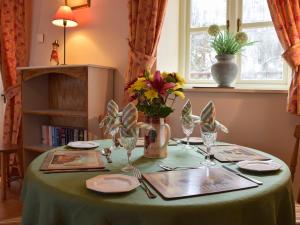 a table with a green table cloth and flowers on it at Gwili Cottage in Llanfynydd