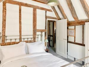 a bedroom with a bed with white sheets at The Knights Apartment, Eastbridge Hospital in Canterbury